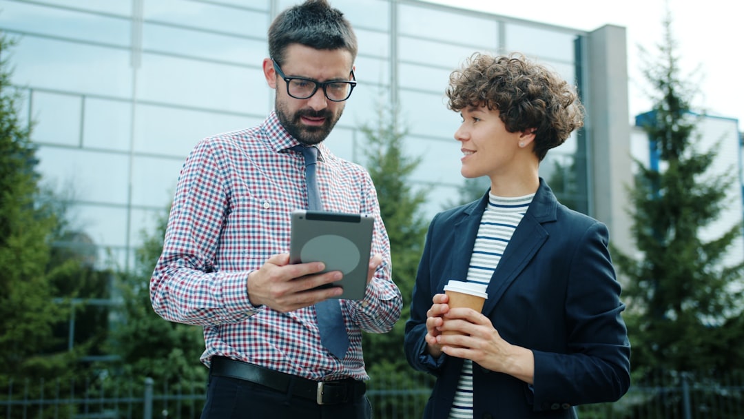 Man and woman discussing tablet outside office building