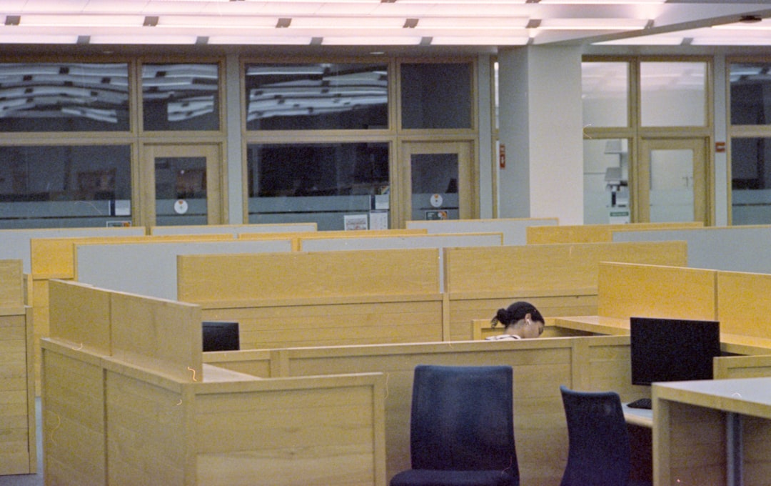 Person sleeping at a desk in a library cubicle.