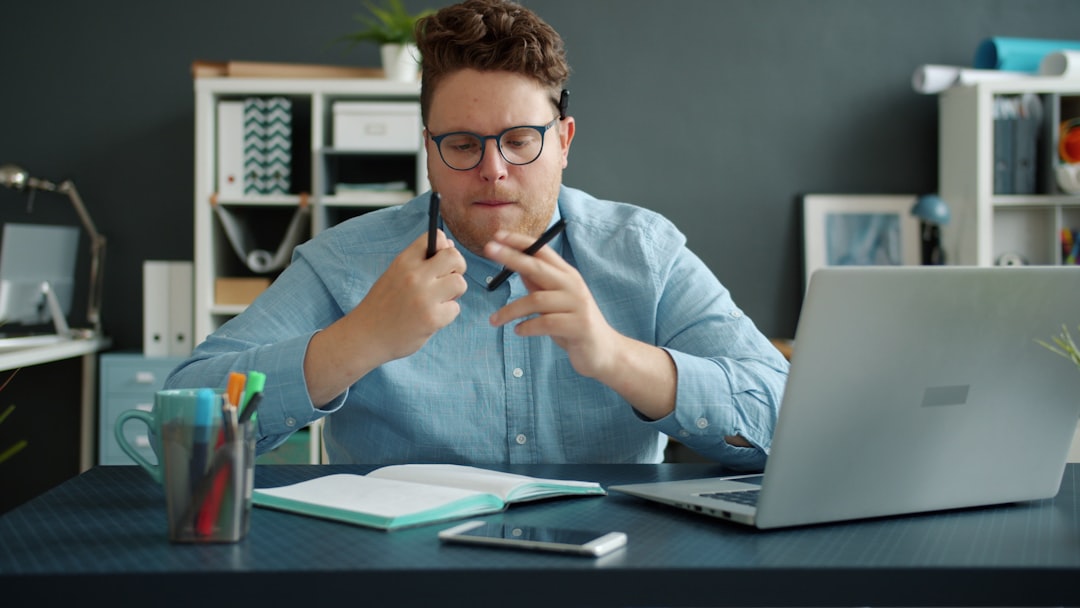 a man holding a pen and a book and a laptop