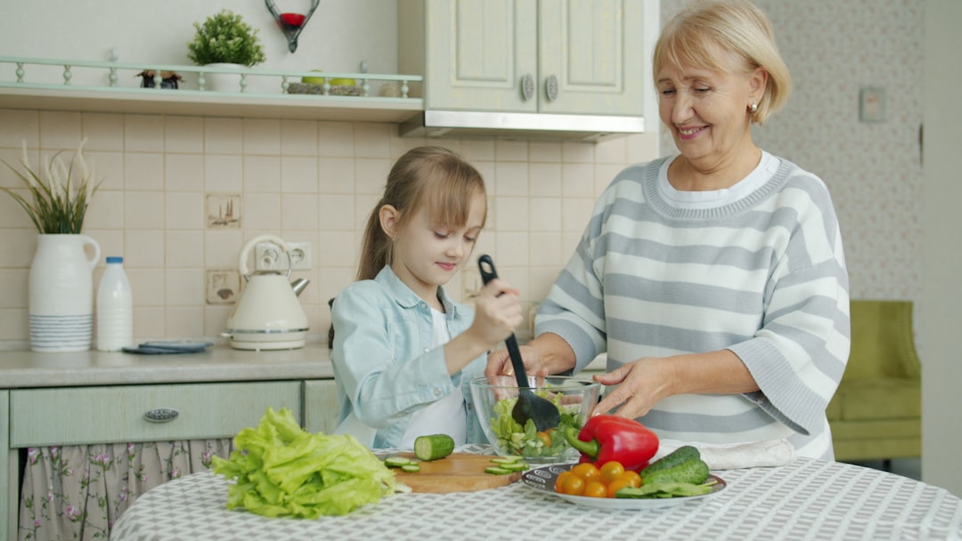 Grandmother and granddaughter making salad together in kitchen.